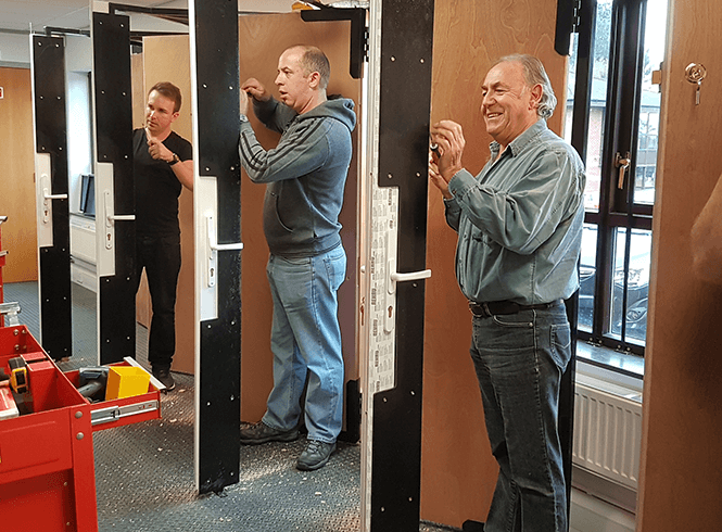 Men training to be locksmiths and practising on doors